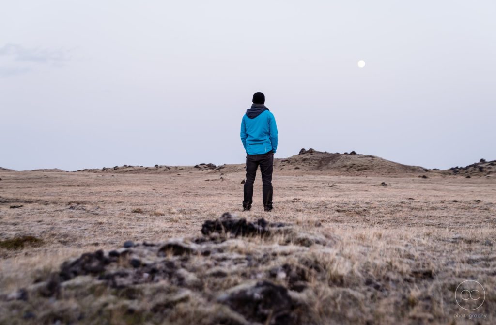 man in blue hoodie standing on brown grass