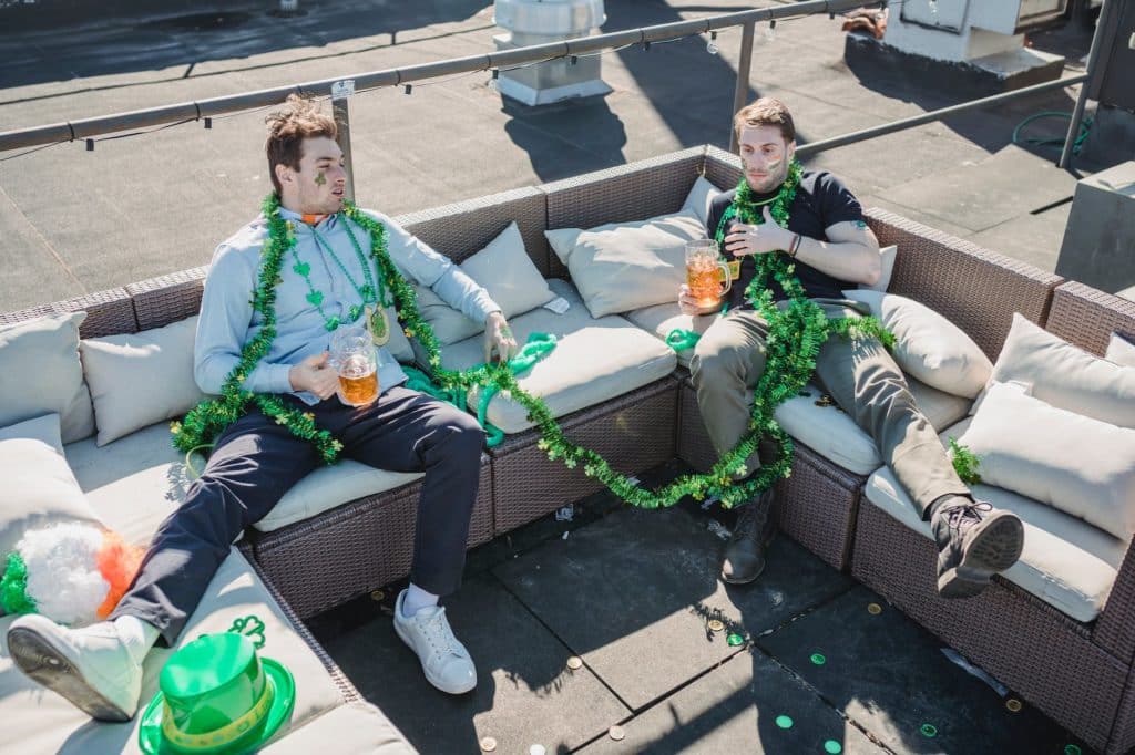young guys lying on couch after beer party on roof