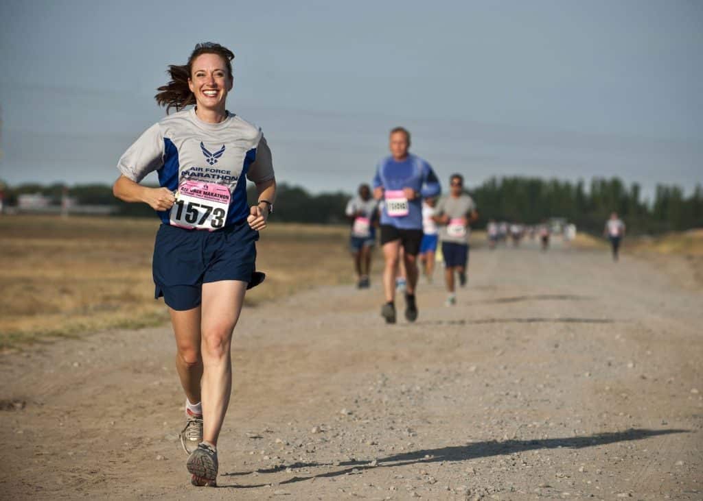 woman in gray crew neck shirt running on brown soil during daytime